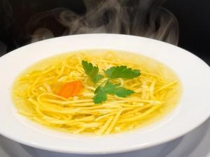 a white bowl of soup with noodles and parsley at Motel i Restauracja "Pod Basztą" in Nagłowice