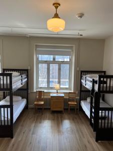a room with three bunk beds and a window at Auberge de Jeunesse des Balcons in Baie-Saint-Paul