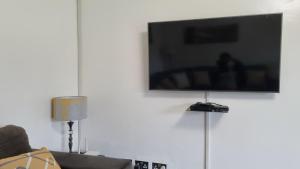 TV de pantalla plana colgada en una pared blanca en Modern and Stylish 2-Bed Cottage in Harare, en Harare