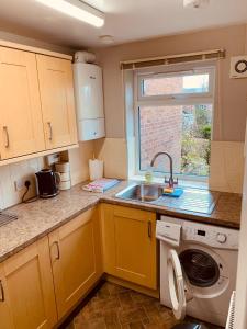 a small kitchen with a sink and a washing machine at 2 bedroom house walking distance to city centre WITH FREE PARKING in York