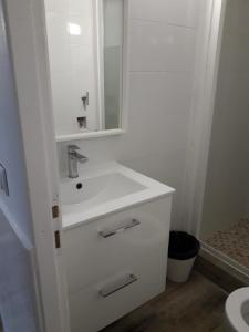 een witte badkamer met een wastafel en een spiegel bij 143 VH in Le Blanc-Mesnil