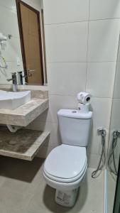 a white bathroom with a toilet and a sink at Pousada Recanto Família in Paraty