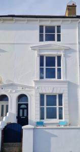 a white house with a blue door and windows at 4 bedroom house opposite the sea in Kent