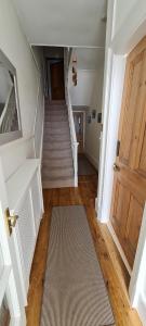 a hallway with a staircase with a door and a rug at 4 bedroom house opposite the sea in Kent