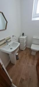 a bathroom with a white sink and a toilet at 4 bedroom house opposite the sea in Kent