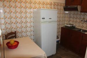 uma cozinha com um frigorífico branco e uma mesa com uma taça de fruta em Cozy double apartment near the sea em Tolo