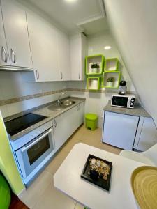 eine Küche mit weißen Schränken und grünen Akzenten in der Unterkunft Ático Deluxe San Ciprian in San Cibrao