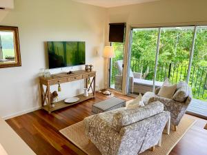 a living room with a couch and a tv at "La Petite Grange" Maleny in Maleny