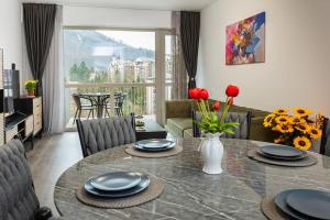 a living room with a dining room table with plates and flowers at Royal Family Apartment in Sinaia