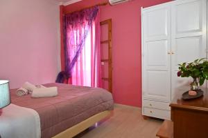 a bedroom with pink walls and a bed and a window at Villa Efterpi in Kontokali