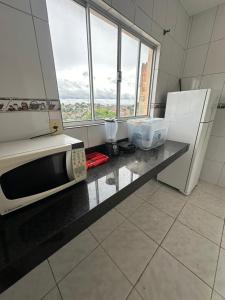 y cocina con encimera, microondas y nevera. en Apart 2 quartos Ribeiro, en Belo Horizonte