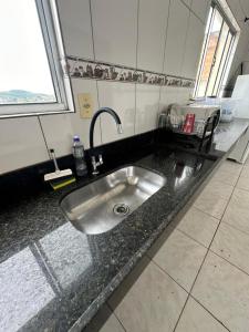 lavabo de acero inoxidable en un baño con ventana en Apart 2 quartos Ribeiro, en Belo Horizonte