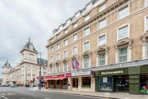 Un edificio con una torre de reloj en una calle de la ciudad. en Mercure London Paddington Hotel, en Londres