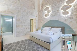 een slaapkamer met een bed en een bakstenen muur bij Vico Bianco Raro Villas Smart Rooms Collection in Ostuni