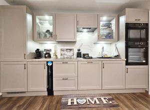 Una cocina con gabinetes blancos y un refrigerador negro. en Apartment - Sleeps 4 - Balcony - AirCon, en Le Kremlin-Bicêtre