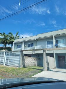 a white house with a balcony and palm trees at Sobrado em ótima localização. in Criciúma