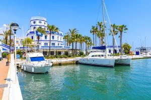 três barcos ancorados numa marina em frente a um edifício em Complejo Vallsun em Estepona