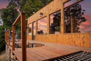 uma casa com um deque de madeira com uma piscina em Casa Terraplen con tina privada y vista a la laguna em Trevelin