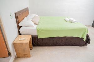 Casa Playa Hermosa في كانكون: سرير مع بطانية خضراء وطاولة خشبية