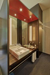 a bathroom with a large sink and a large mirror at Sorell Hotel Rigiblick - Studios & Spa Suites in Zurich