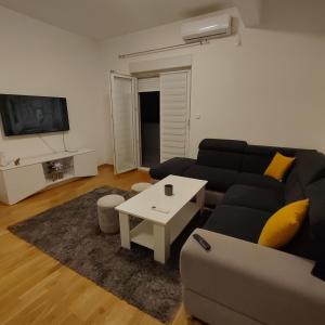 sala de estar con sofá negro y mesa en Apartman Ena, en Bileća