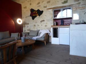 uma cozinha e sala de estar com um sofá e uma mesa em Les Oiseaux de Passage em Chaillevois