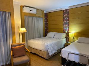 um quarto de hotel com duas camas e uma cadeira em Flat próximo Congonhas em São Paulo