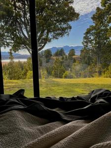 a bed in a room with a view of a field at Casa de Campo con tina de agua caliente in Trevelin