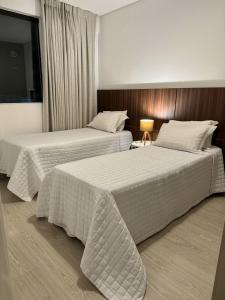 Gontijo Apart Hotel في إيتاجوبا: سريرين يجلسون بجانب بعض في غرفة