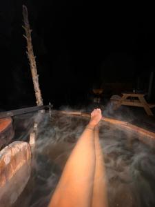 a persons legs in a hot tub at night at Casa de Campo con tina de agua caliente in Trevelin