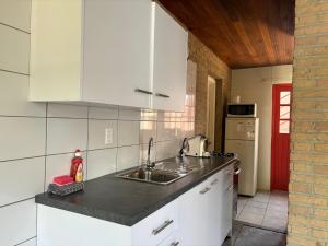 una cocina con armarios blancos y fregadero en Advantage Apartments Curacao, en Willemstad