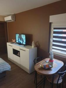 een woonkamer met een tafel en een tv op een kast bij Studio apartman Alisa in Ðakovo