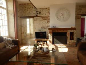 a living room with a fireplace and a clock on the wall at Les Oiseaux de Passage in Chaillevois