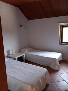 1 dormitorio con 2 camas, mesa y ventana en Casa de Andrães - Glicíneas, en Marco de Canaveses