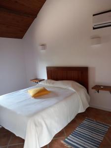 1 dormitorio con 1 cama blanca grande y cabecero de madera en Casa de Andrães - Glicíneas, en Marco de Canaveses