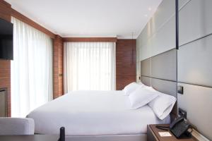 1 dormitorio con 1 cama blanca y teléfono en Hotel MyPalace León en León