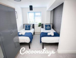 a bedroom with two beds with blue and white sheets at Cocoonstays Short Lets and Serviced Accommodation Luton in Luton