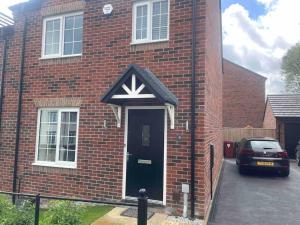 a brick house with a black door with a x on it at Stay@Chesterfield in Wingerworth