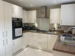 a kitchen with white cabinets and a sink at Stay@Chesterfield in Wingerworth