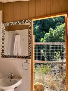 a bathroom with a mirror and a sink and a window at Cabaña ecológica y aislada in Santiago