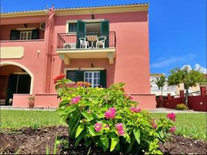 a pink house with pink flowers in front of it at Alexandra's Apartments by Exclsv in Sidari