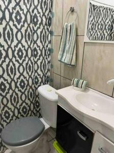 a bathroom with a toilet and a sink at Casa de praia p/ família, confortável, bem arejada in Serra