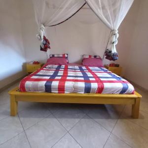 a bed with a red white and blue striped comforter at Bukoto Private Room in Kampala