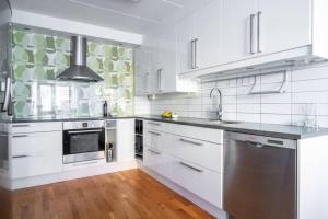 una cocina con armarios blancos y electrodomésticos de acero inoxidable en Ett mysigt hus i centrala Borås! (Hela Boendet) en Borås