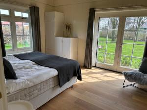 Villa Nieuwland holiday home في دن أوفر: غرفة نوم بسرير ونوافذ كبيرة