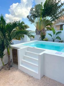 a white swimming pool with stairs next to a white house at Villa NOMA - Apartment w/ Lovely View I 5 min/Beach I Free SUP in Willemstad