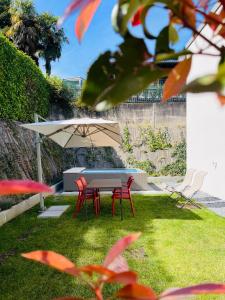 stół z 2 krzesłami i parasol na dziedzińcu w obiekcie Appartamento di lusso su 2 livelli con mini piscina esterna a 5 min da Tasis w mieście Montagnola