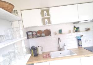 a kitchen counter with a sink and white cabinets at La Fremille - Nid nature - Piscine & terrasse - 400m gare Paris in Saint-Cyr-lʼÉcole