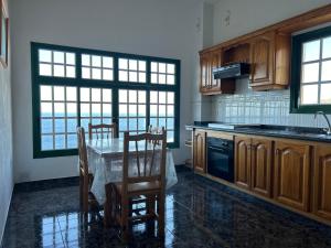 a kitchen with a table and chairs and a kitchen with windows at Pozo de las Calcosas - El Hierro in Pozo de las Calcosas