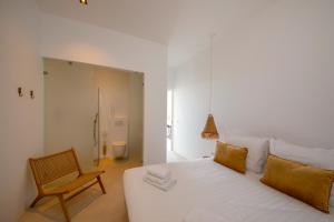 a bedroom with a white bed and a chair at Villa NOMA - Apartment w/ Lovely View I 5 min/Beach I Free SUP in Willemstad